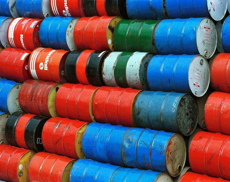 Stacked colorful oil drums in red, blue, green, and black; weathered and rusty in places.