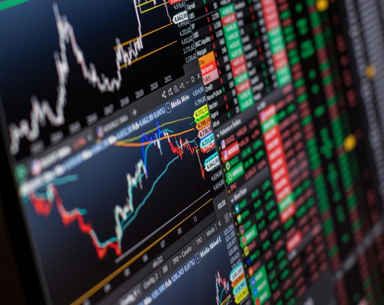 Stock market trading screen showing price charts and a column of green and red tickers for real-time quotes.