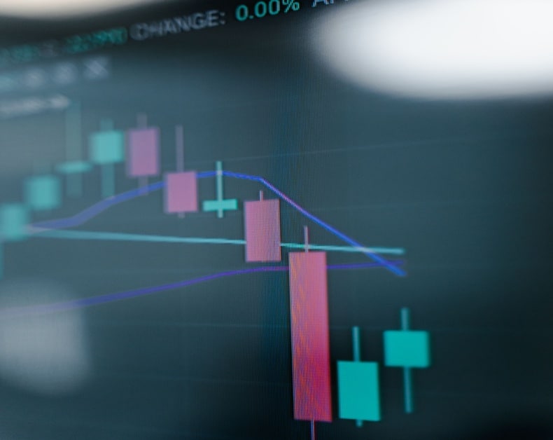 Close-up of a stock chart with pink and teal candlesticks and moving-average lines on a dark background.